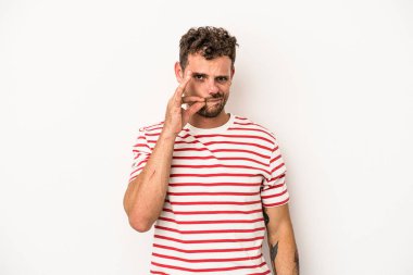 Beyaz arka planda izole edilmiş beyaz tenli genç bir adam parmakları dudaklarında bir sır saklıyor..