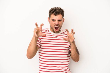 Beyaz arka planda izole edilmiş genç beyaz bir adam pençelerini kedi taklidi yaparken gösteriyor, agresif bir hareket..