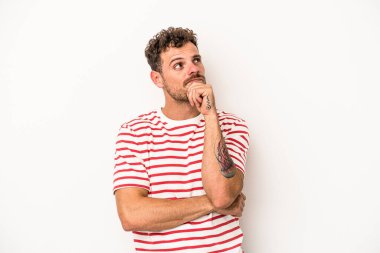 Beyaz arka planda soyutlanmış genç beyaz bir adam düşünüyor ve yukarı bakıyor, yansıtıyor, düşünüyor, hayal kuruyor..