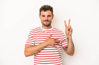 Beyaz arka planda izole edilmiş genç beyaz adam yemin ediyor, elini göğsüne koyuyor..