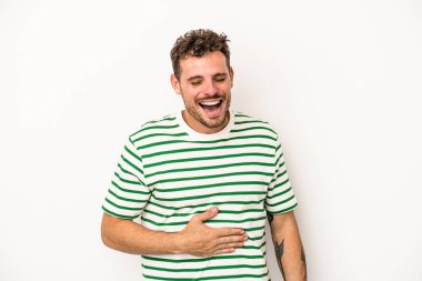 Beyaz arka planda izole edilmiş genç beyaz adam karnına dokunuyor, nazikçe gülümsüyor, yemek yiyor ve tatmin oluyor..