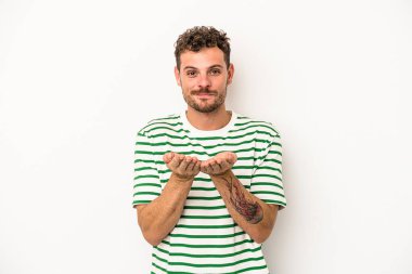 Beyaz arka planda izole edilmiş genç beyaz bir adam elinde avuç içi bir şeyle kameraya sunuyor..