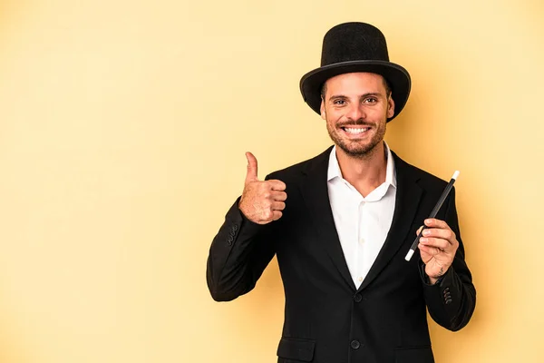 Young Caucasian Wizard Holding Wand Isolated Yellow Background Smiling Raising — Stock Photo, Image