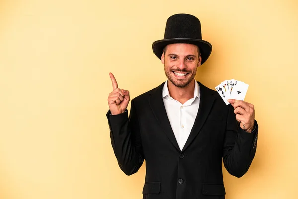 Young Caucasian Wizard Holding Magic Card Isolated Yellow Background Smiling — Stock Photo, Image