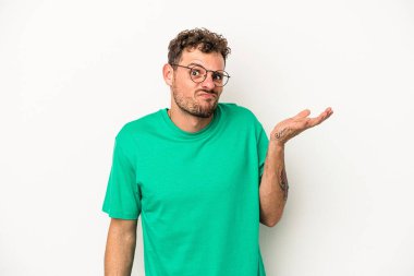 Beyaz arka planda izole edilmiş genç beyaz bir adam sorgulama sırasında omuz silkiyor ve şüphe duyuyor..