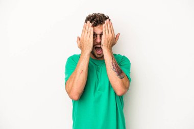 Beyaz arka planda izole edilmiş genç beyaz bir adam yüzünün yarısını palmiye ile örterek eğleniyor..