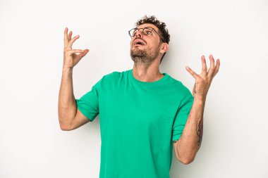 Beyaz arka planda izole edilmiş genç beyaz adam gökyüzüne haykırıyor, yukarı bakıyor, hayal kırıklığına uğramış..