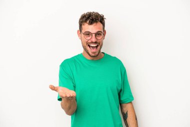 Beyaz arka planda izole edilmiş genç beyaz bir adam selamlama jesti olarak kameraya elini uzatıyor..