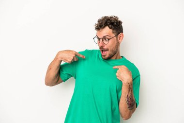 Beyaz arka planda izole edilmiş genç beyaz bir adam parmağını göstererek şaşırdı, geniş bir gülümsemeyle..