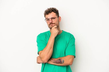 Beyaz arka planda izole edilmiş genç beyaz bir adam şüpheli, belirsiz, seni muayene ediyor..