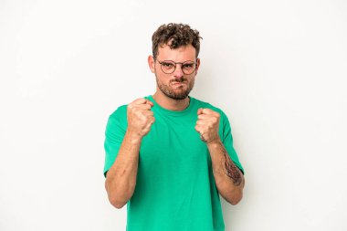 Beyaz arka planda izole edilmiş genç beyaz bir adam yumruğunu kameraya gösteriyor, agresif bir yüz ifadesi..