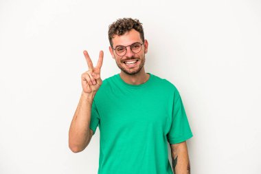 Beyaz arka planda izole edilmiş genç beyaz adam iki numarayı parmaklarıyla gösteriyor..
