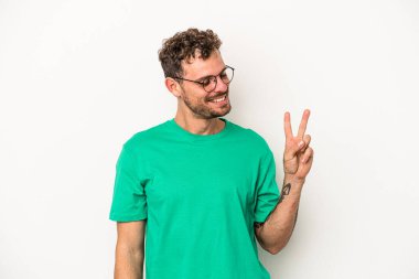 Beyaz arka planda izole edilmiş genç beyaz bir adam neşeli ve kaygısız parmakları olan bir barış sembolü gösteriyor..