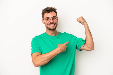 Beyaz arka planda izole edilmiş genç beyaz bir adam güçlü bir hareket gösteriyor, kollarıyla, kadınsı gücün sembolü.