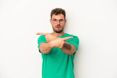 Beyaz arka plan noktalarında izole genç beyaz adam, iki seçenek arasında seçim yapmaya çalışıyor.