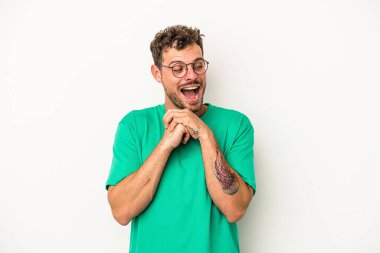 Beyaz arka planda izole genç beyaz adam ellerini çenesinin altında tutuyor, mutlu bir şekilde yana bakıyor..