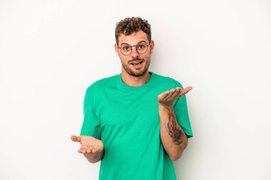 Beyaz arka planda izole genç beyaz adam kollarıyla ölçek yapar, mutlu ve kendinden emin hisseder..