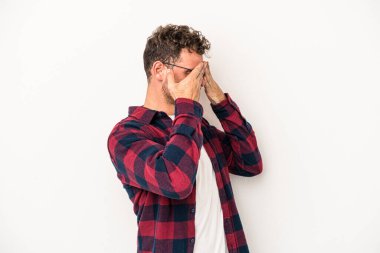 Beyaz arka planda izole edilmiş genç beyaz bir adam elleriyle gözlerini kapatmaktan korkuyor..