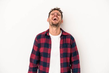 Beyaz arka planda izole edilmiş genç beyaz adam gevşemiş ve mutlu bir şekilde gülüyor, boynunda dişlerini gösteriyor..