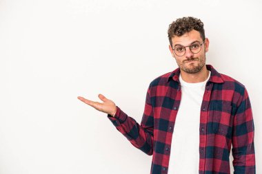 Beyaz arka planda izole edilmiş genç beyaz bir adam bir palmiye üzerinde fotokopi alanı gösteriyor ve belinde başka bir el tutuyor..