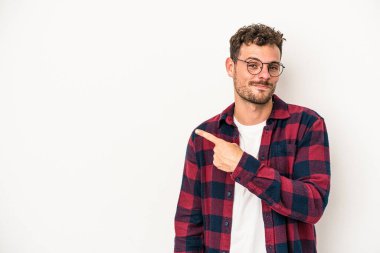 Beyaz arka planda izole edilmiş genç beyaz bir adam gülümsüyor ve boş alanda bir şeyler gösteriyor..