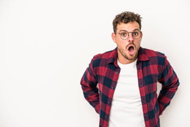 Beyaz arka planda izole edilmiş genç beyaz adam gördüğü bir şey yüzünden şoka uğruyor..