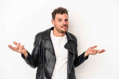 Beyaz arka planda izole edilmiş genç beyaz bir adam sorgulama sırasında omuz silkiyor ve şüphe duyuyor..