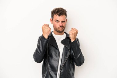 Beyaz arka planda izole edilmiş genç beyaz bir adam yumruğunu kameraya gösteriyor, agresif bir yüz ifadesi..
