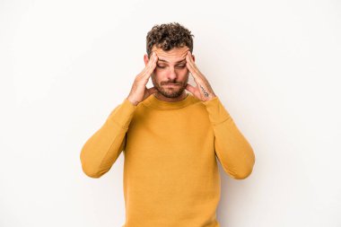 Beyaz arka planda izole olmuş genç beyaz bir adam başı ağrıyor, yüzüne dokunuyor..