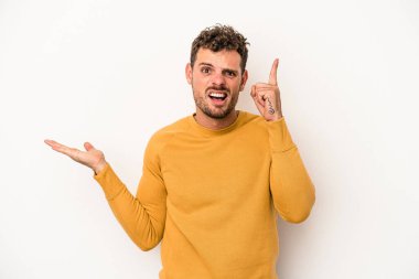 Beyaz arka planda izole edilmiş genç beyaz bir adam elinde bir ürün tutuyor ve.