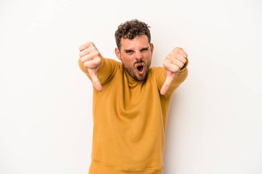 Beyaz arka planda izole edilmiş genç beyaz bir adam baş parmağını aşağı gösteriyor ve hoşlanmadığını ifade ediyor..