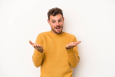 Beyaz arka planda izole edilmiş genç beyaz bir adam elinde avuç içi bir şeyle kameraya sunuyor..