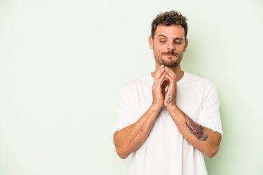 Kafkasyalı genç bir adam yeşil arka planda izole edilmiş bir plan yapıyor, bir fikir kuruyor..