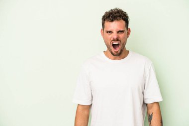 Kafkas 'lı genç adam yeşil arka planda izole edilmiş çok kızgın, öfkeli, hayal kırıklığına uğramış bağırıyor..