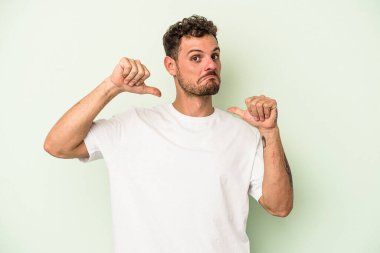 Yeşil arka planda izole genç beyaz adam gururlu ve kendinden emin hissediyor, örnek olarak..
