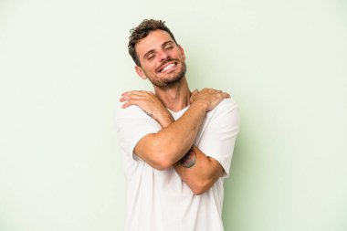 Kafkasyalı genç adam yeşil arka planda izole edilmiş, güler yüzlü ve mutlu..