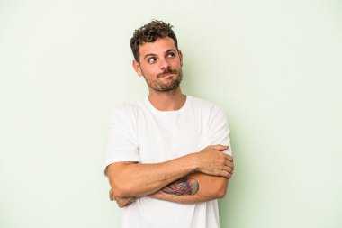 Yeşil arka planda izole edilmiş genç beyaz adam hedeflere ve amaçlara ulaşmayı hayal ediyor.