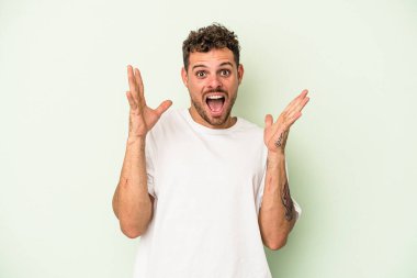 Kafkasyalı genç adam yeşil arka planda izole edilmiş gökyüzüne bağırıyor, yukarı bakıyor, hayal kırıklığına uğramış..