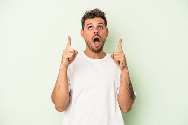 Yeşil arka planda izole edilmiş beyaz bir adam ağzı açık bir şekilde üst tarafı işaret ediyor..