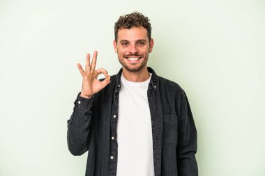 Genç beyaz adam yeşil arka planda izole edilmiş neşeli ve kendinden emin..