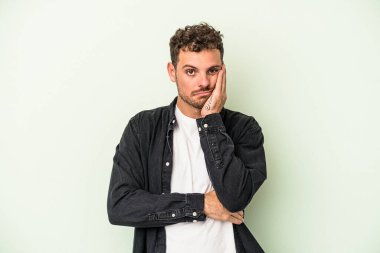 Yeşil arka planda izole edilmiş genç beyaz adam sıkılmış, yorgun ve dinlenmeye ihtiyacı var..