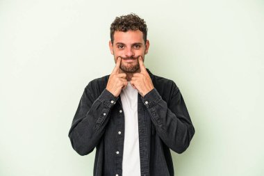 Kafkasyalı genç adam yeşil arka planda izole edildi. İki seçenek arasında şüphe var..