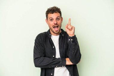 Kafkasyalı genç adam yeşil arka planda izole edilmiş. Harika bir fikri var. Yaratıcılık kavramı..