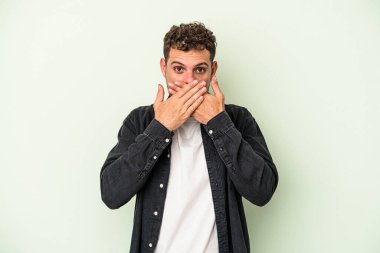 Kafkasyalı genç adam yeşil arka planda izole edilmiş ağzı kapalı ve elleri endişeli görünüyor..