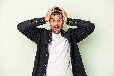 Genç beyaz adam yeşil arka planda izole edilmiş bağırıyor, çok heyecanlı, tutkulu, bir şeyden memnun..