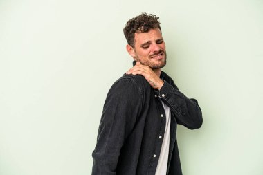 Yeşil arka planda izole edilmiş, omuz ağrısı olan genç beyaz bir adam..