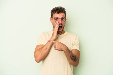 Kafkasyalı genç adam yeşil arka planda izole edilmiş. Dedikodu yapıyor, bir şeyleri bildiriyor..