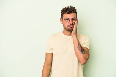 Yeşil arka planda izole edilmiş, üzgün ve dalgın hisseden, fotokopi alanına bakan genç beyaz adam..