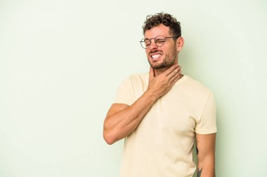 Kafkasyalı genç adam yeşil arka planda izole edilmiş kafasının arkasına dokunuyor, düşünüyor ve bir seçim yapıyor..