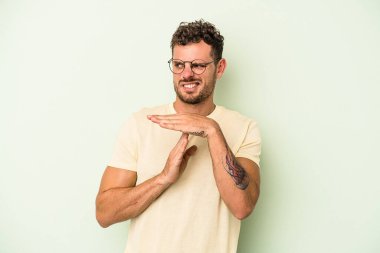 Yeşil arka planda izole edilmiş genç beyaz bir adam bir mola hareketi gösteriyor..